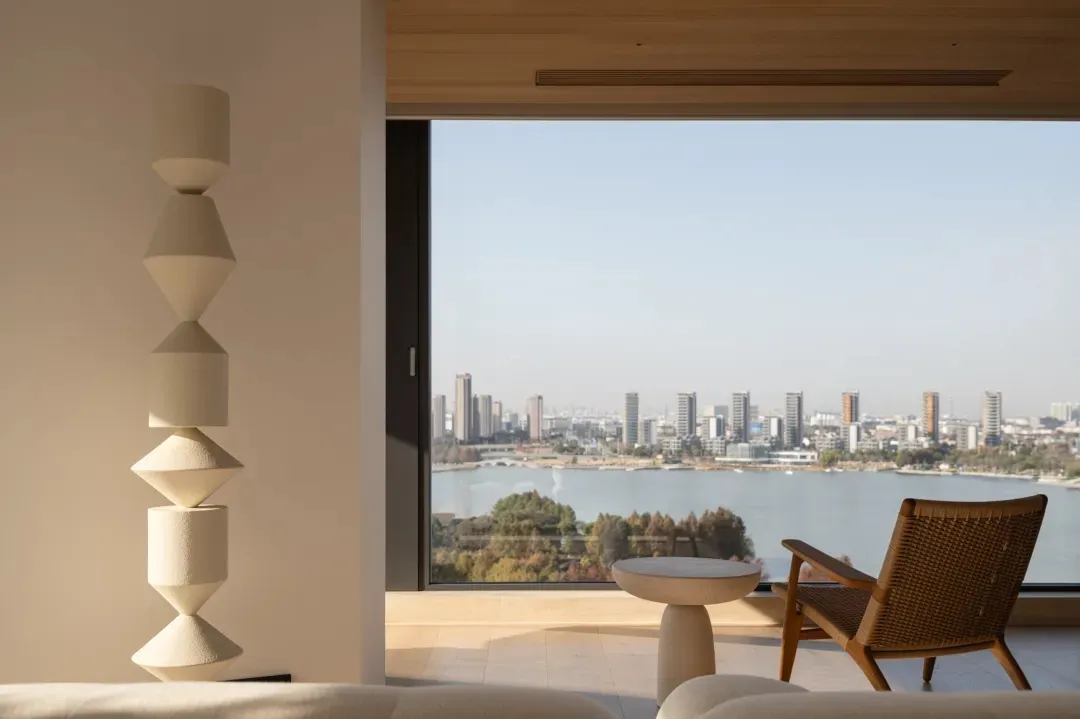 一間現代客廳，擺放著沙發、椅子和餐桌，透過大窗戶欣賞城市景觀，木材和玻璃元素，自然光線充足