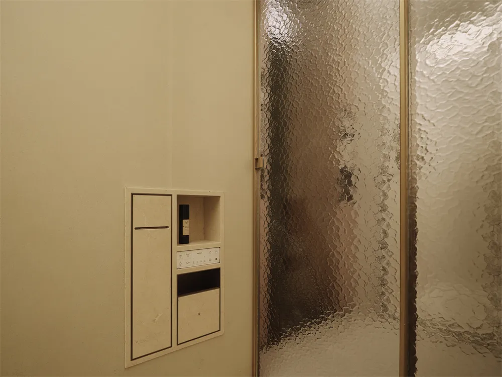 Bathroom with a glass shower stall, tan color scheme, and bright lighting