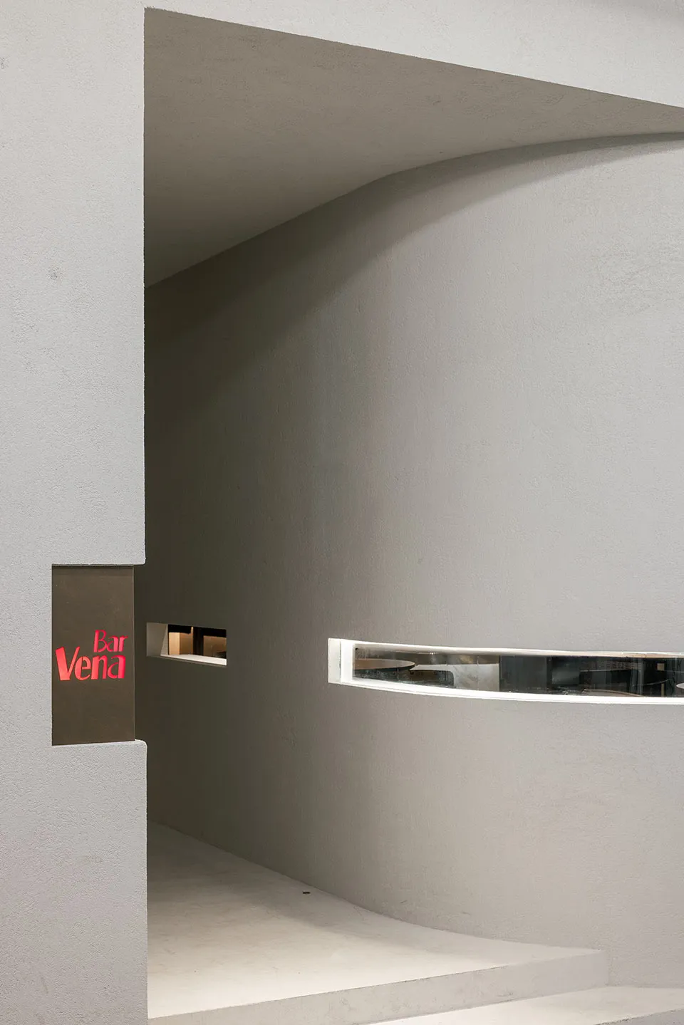 Cozy dimly-lit bar with a red sign on a concrete wall