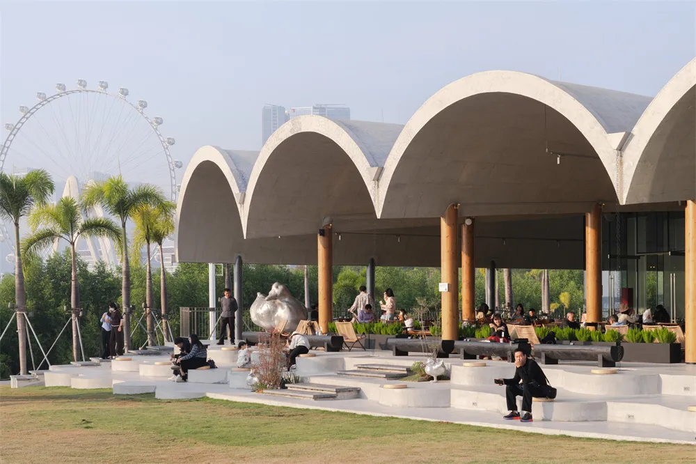 一間具有高天花板和開闔空間的人潮盈濃，擺放著餐桌和椅子，主要以白色調為主，伴隨著溫和的柔和燈光的建築