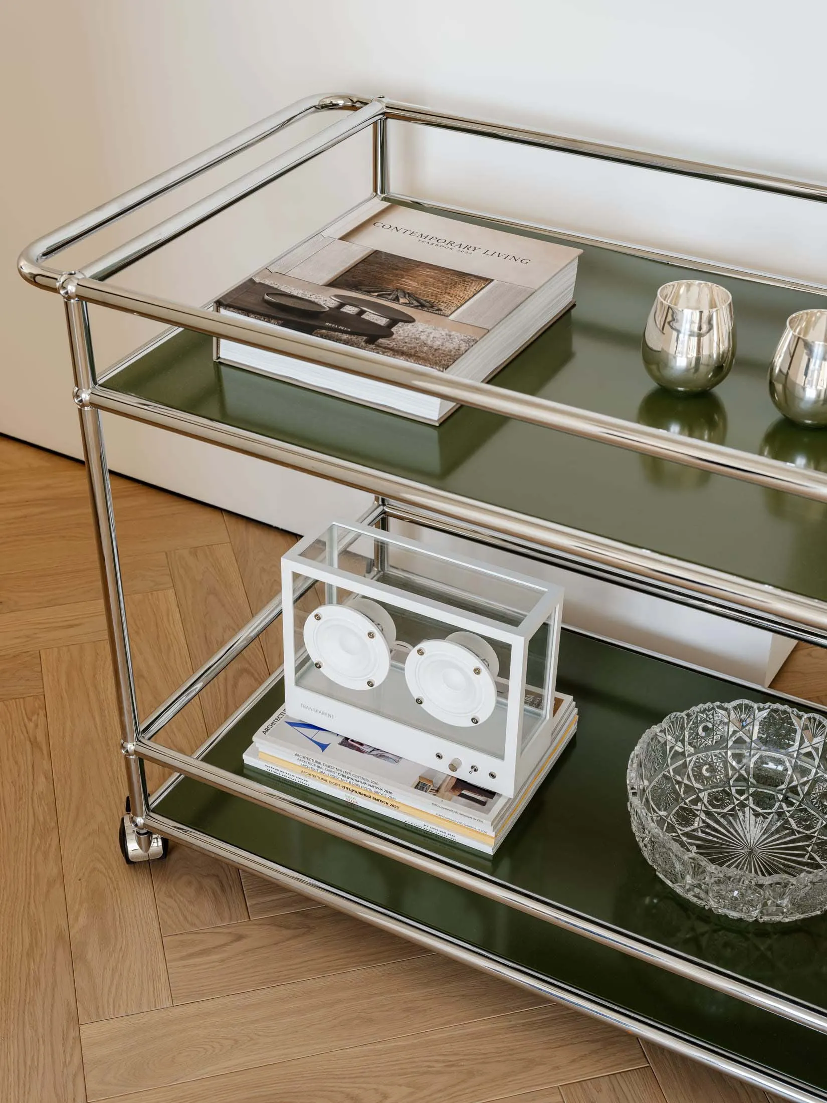 A well-lit living space with a green shelf holding a book, a bowl, and a vase, arranged in a visually appealing manner, with natural light coming in through a window