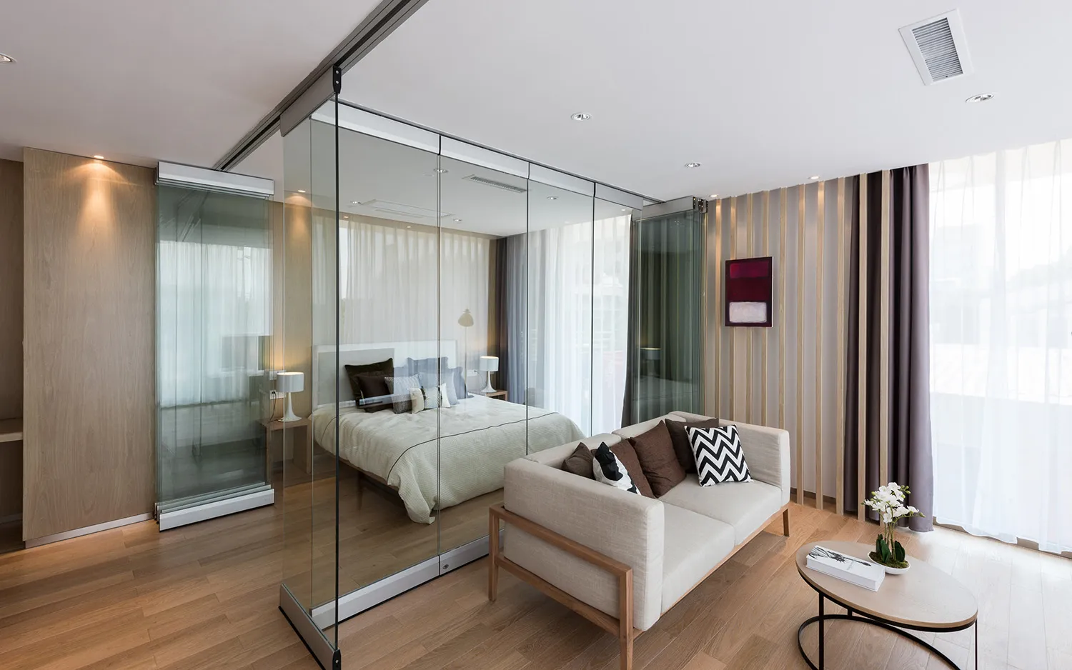 A well-lit living room with a couch, bed, and chair, arranged to maximize space, and a large glass door that brings in natural light