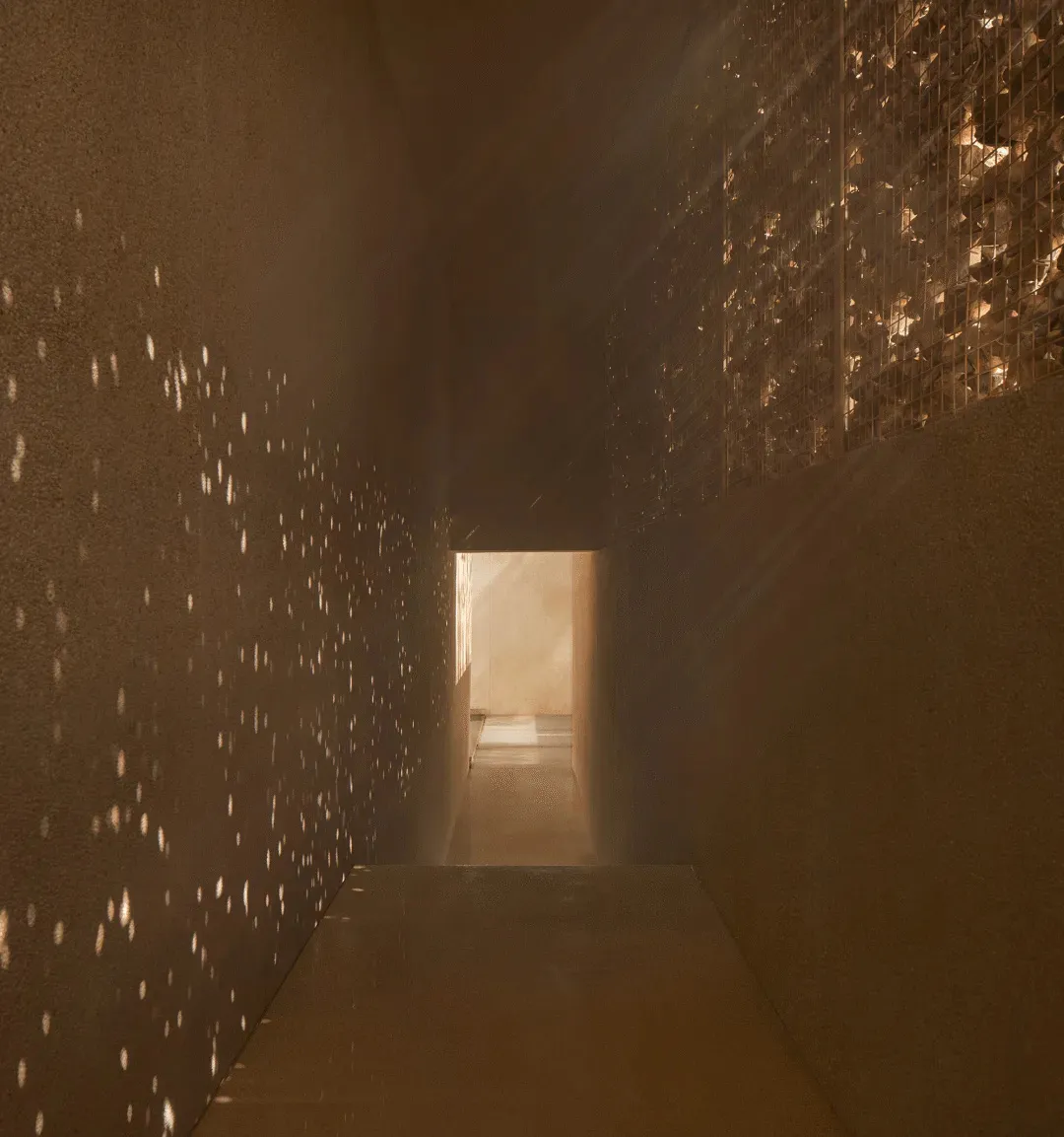 A simple functional hallway with concrete walls, lights on the wall, and a doorway leading to another room, creating a warm and inviting atmosphere
