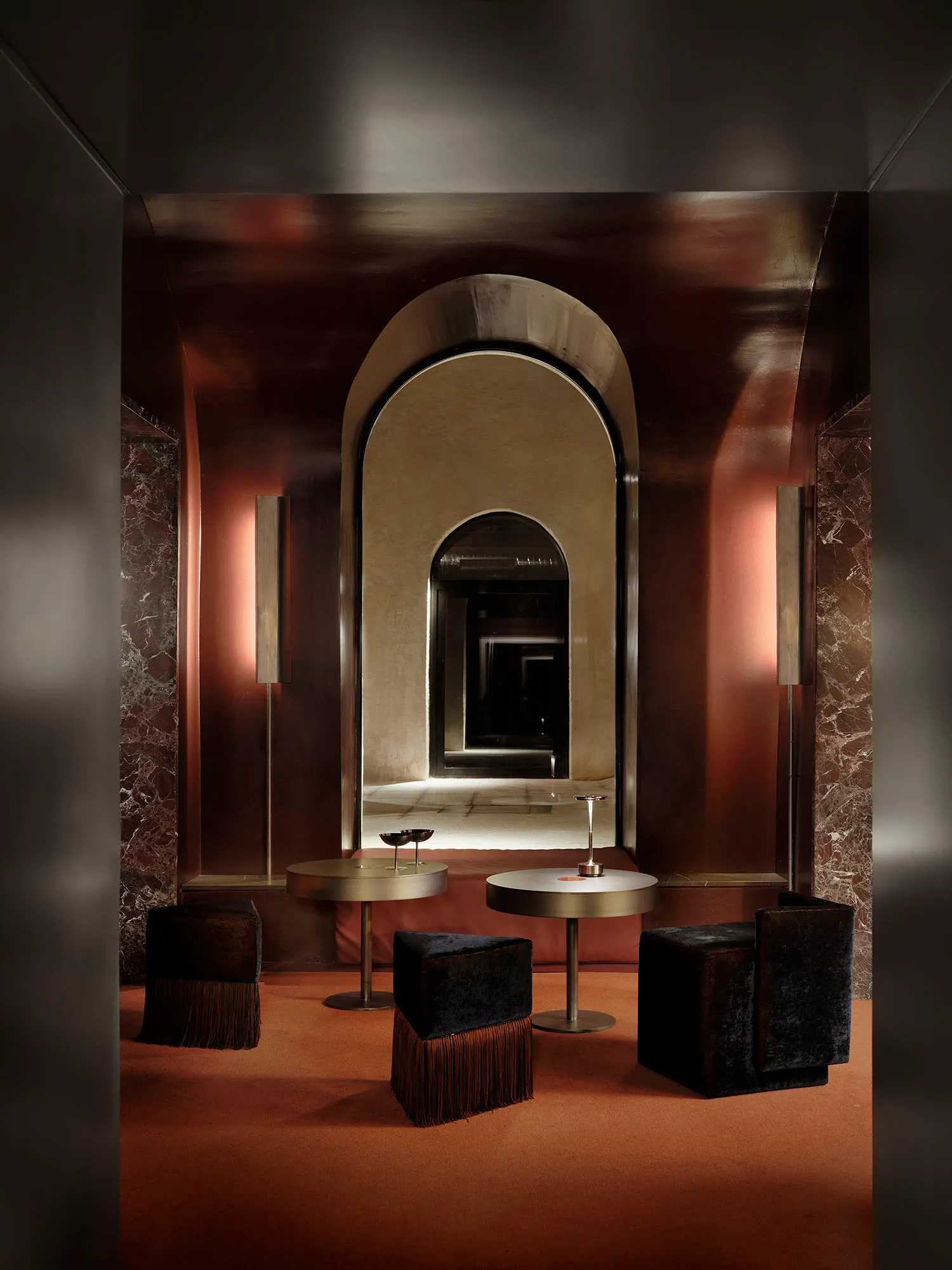A modern living dining area with a brown color scheme, featuring a large arched doorway, a mirror, and a table with chairs, surrounded by a well-lit space with natural light