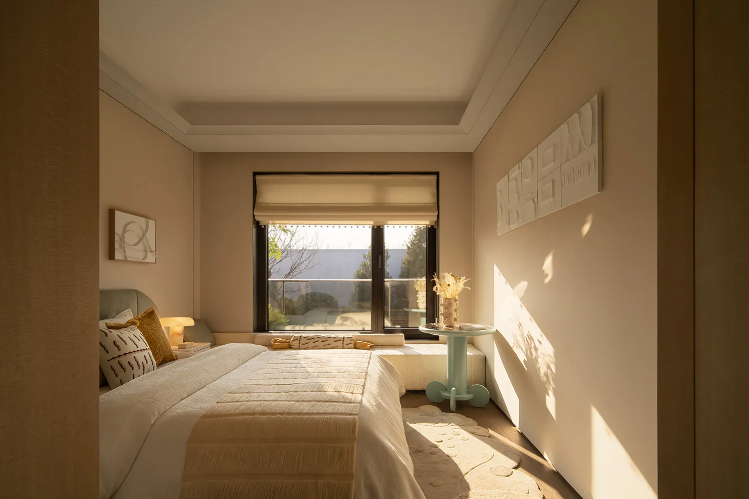 A well-lit bedroom with a modern style, featuring a white comforter, a table, and a potted plant, with a cozy and inviting atmosphere