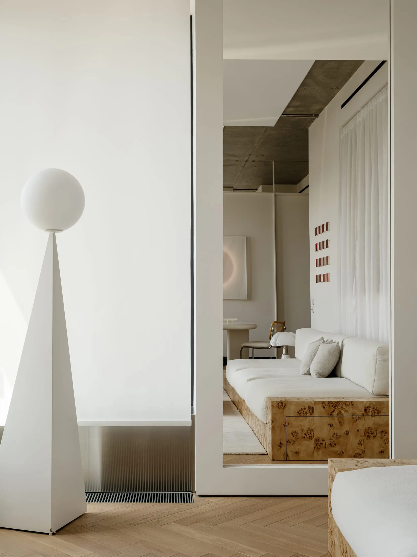A modern living room with a white couch and chair, surrounded by white walls and soft, diffused lighting, creating a comfortable and inviting atmosphere