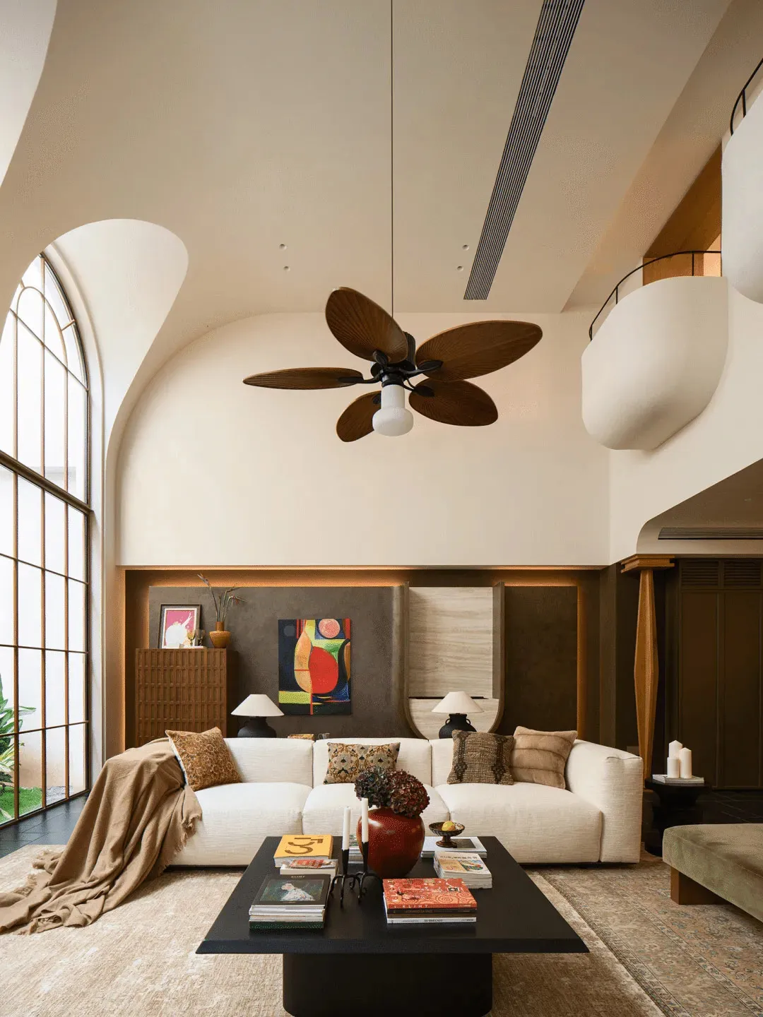 A well-lit living room with a white couch, coffee table, and ceiling fan, creating a comfortable and inviting atmosphere