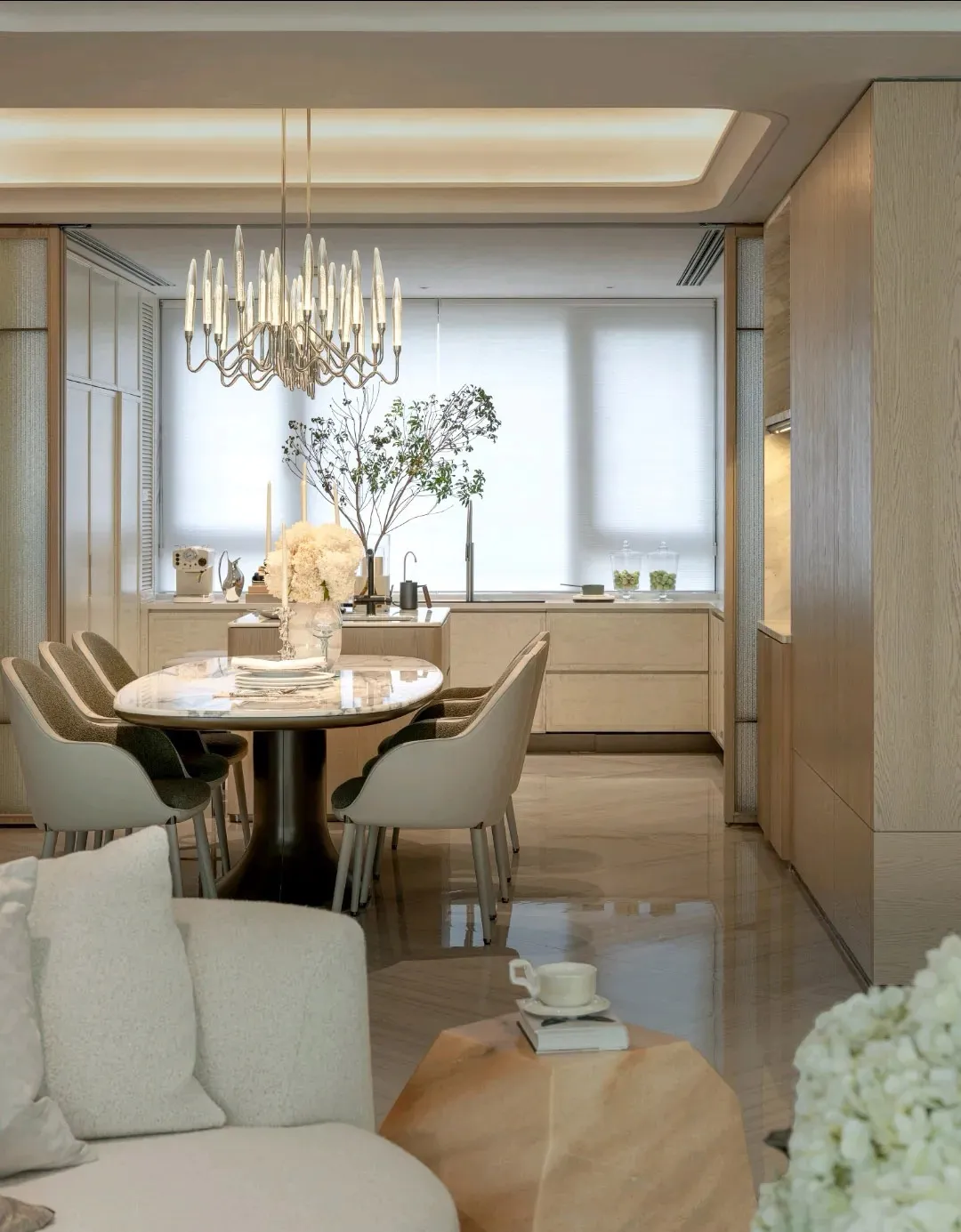 A modern living room with a dining area, featuring a dining table, couch, chair, and potted plant, with a clean and minimalist design and warm lighting