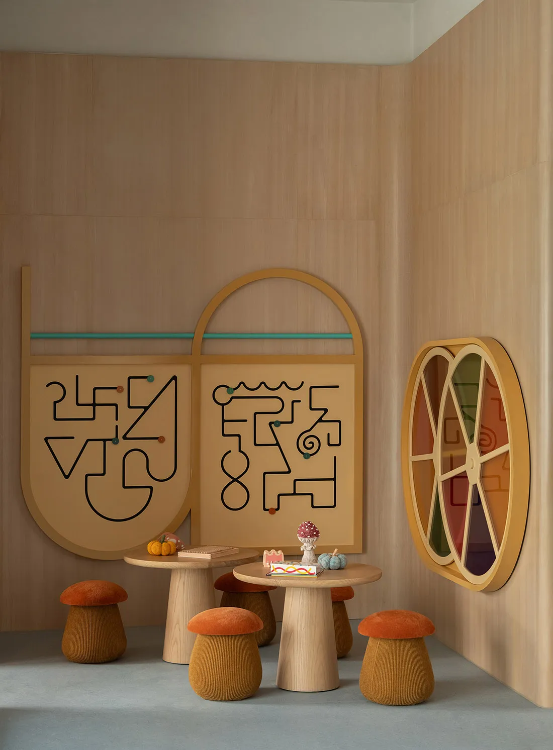 A modern dining room with a wooden table and chairs, set with a cake and oranges, and a mirror on the wall, with natural lighting