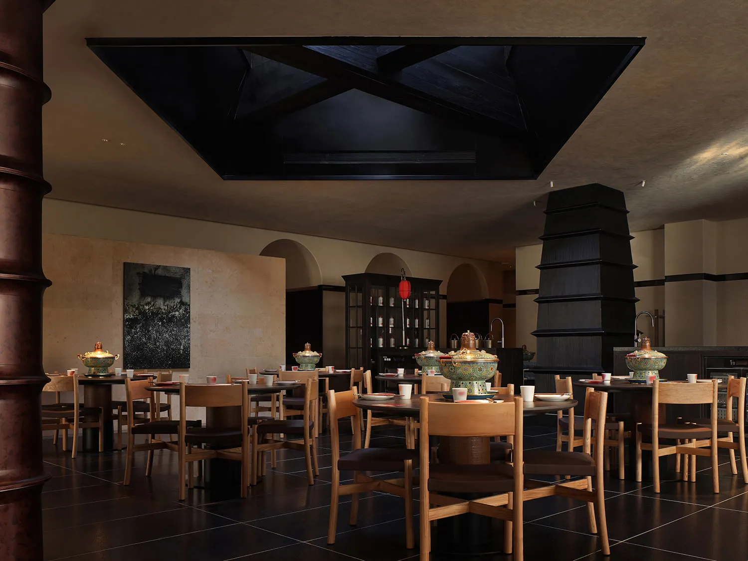 一間現代餐廳的餐廳區域，擁有一個擁擠的餐桌和椅子，桌上擺放各種物品，柔和溫暖的燈光創造出溫馨的氣氛