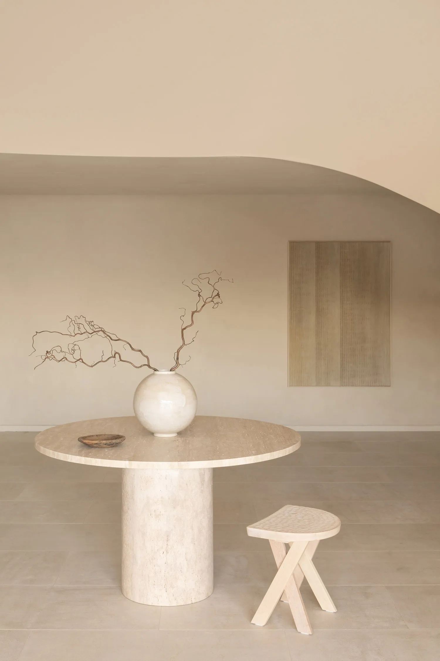 A minimalist dining area with a white table, a ceramic vase, and a couch and chair, surrounded by soft and diffused lighting