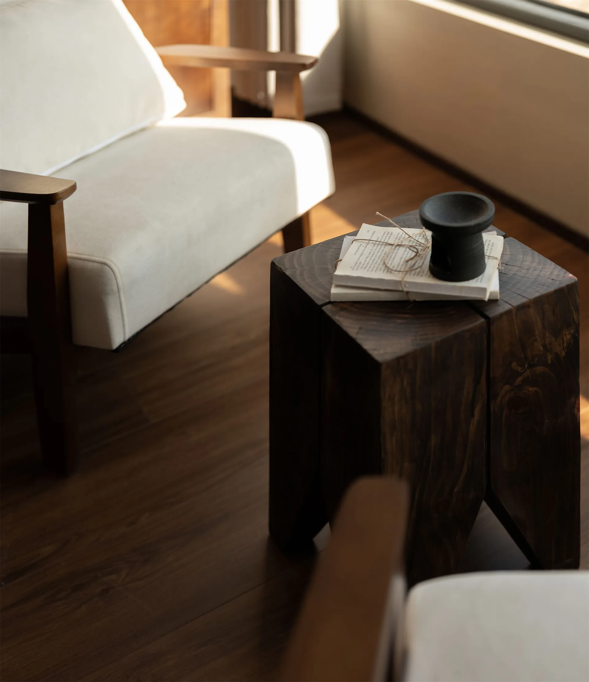 A well-lit living room with a white couch, wooden coffee table, and a chair, set against a neutral background