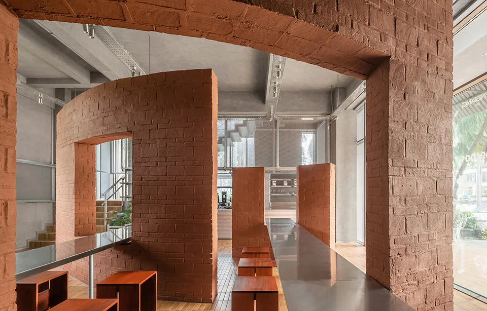 Rustic dining space with brick walls, stone archway, wooden tables and benches, and natural light
