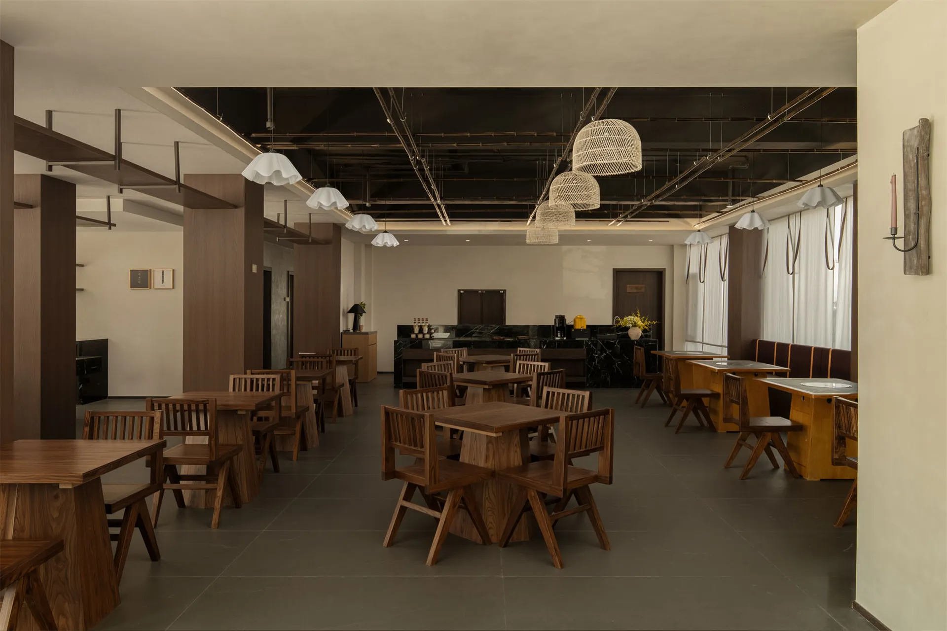 A modern restaurant with a large dining area featuring wooden tables and chairs, well-lit to create a warm and inviting atmosphere