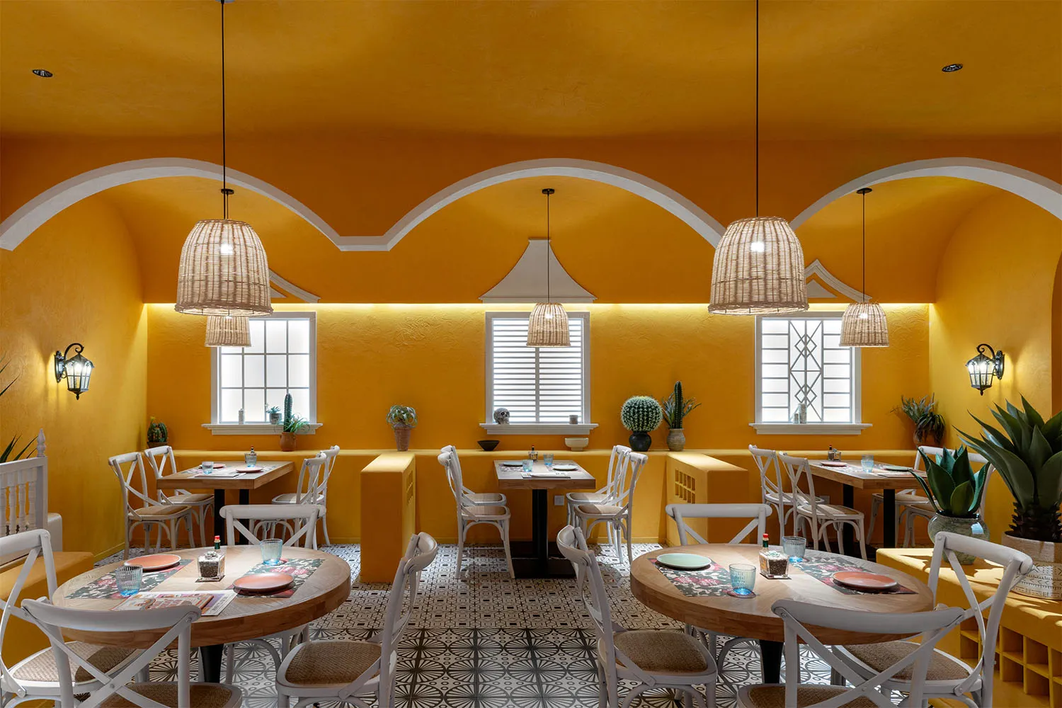 A modern restaurant with a warm yellow color scheme, featuring a dining area with tables and chairs, potted plants, and a welcoming atmosphere