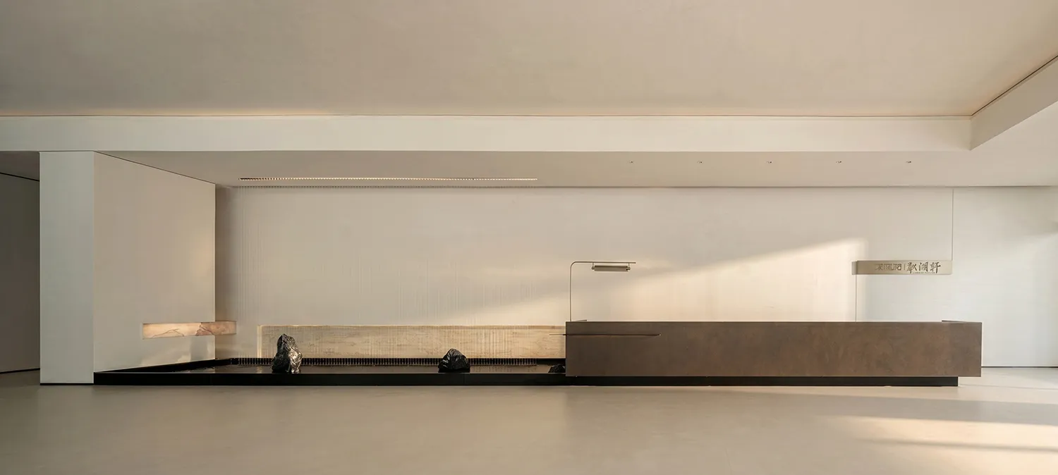 A cozy living space with a brown wooden bench and table, surrounded by a white wall and natural light from a window