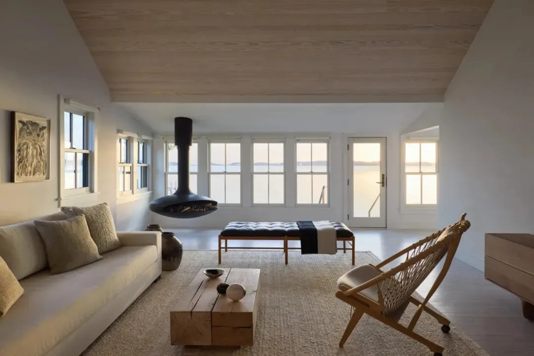 Comfortable living space with a large window, modern furniture, and natural light, decorated with vases, bowls, and a bottle
