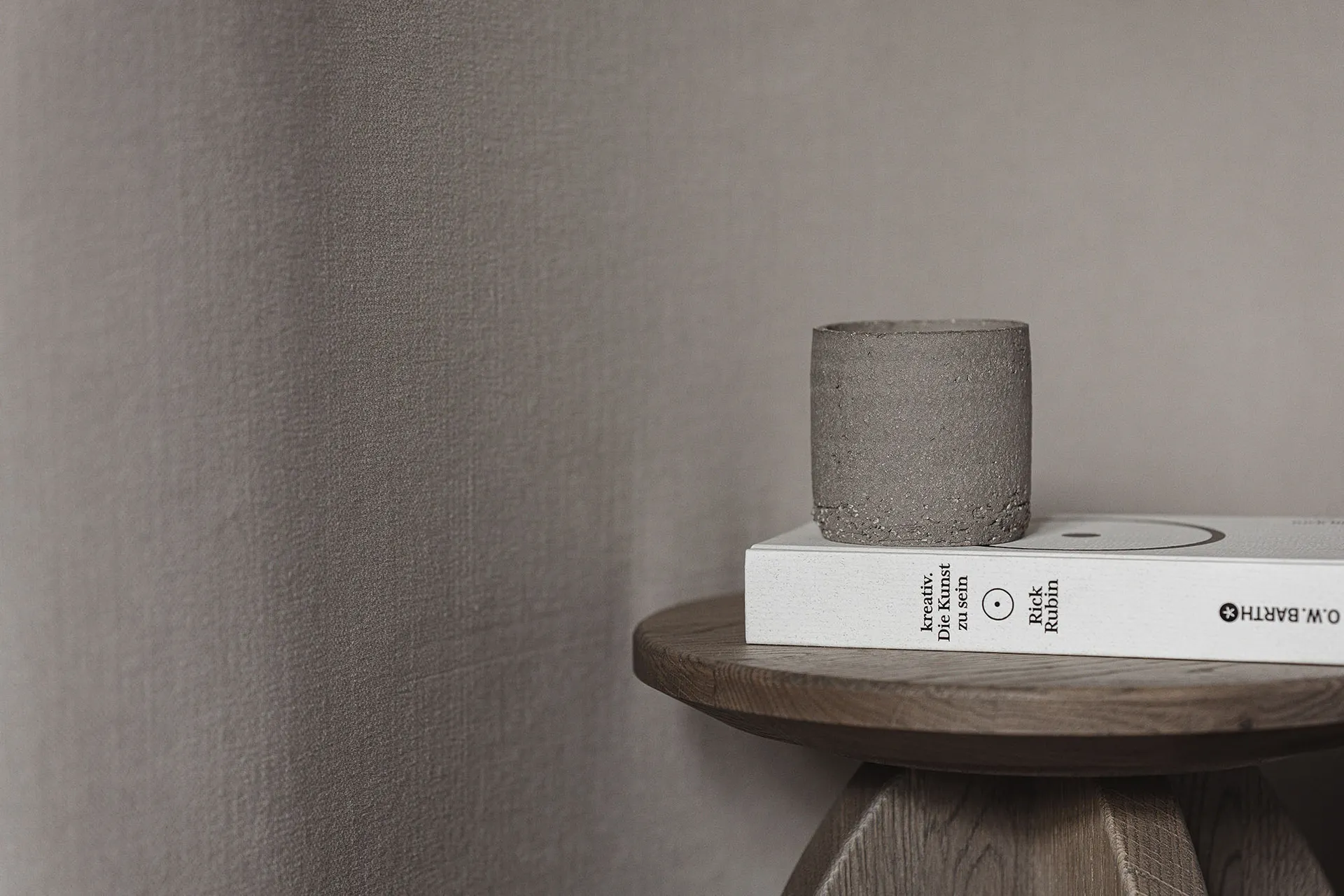 A wooden table with a book, vase, and cup on it, set in a cozy and comfortable space