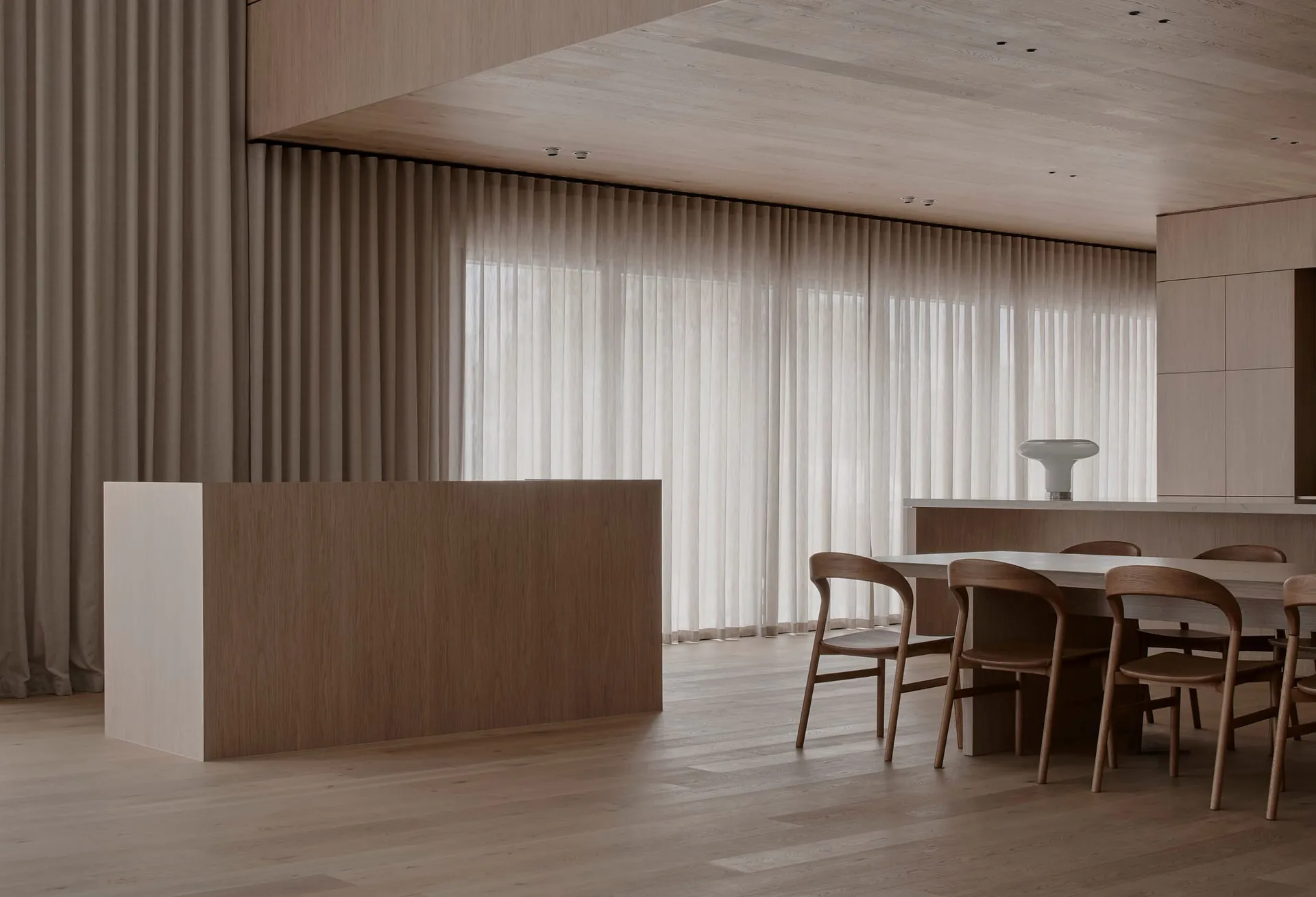 Warm and inviting kitchen with a wooden floor, wooden cabinets, and a dining table surrounded by chairs, under natural light