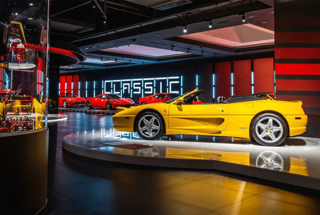 A modern showroom displaying various sports cars, including a yellow convertible, with a sleek and luxurious atmosphere