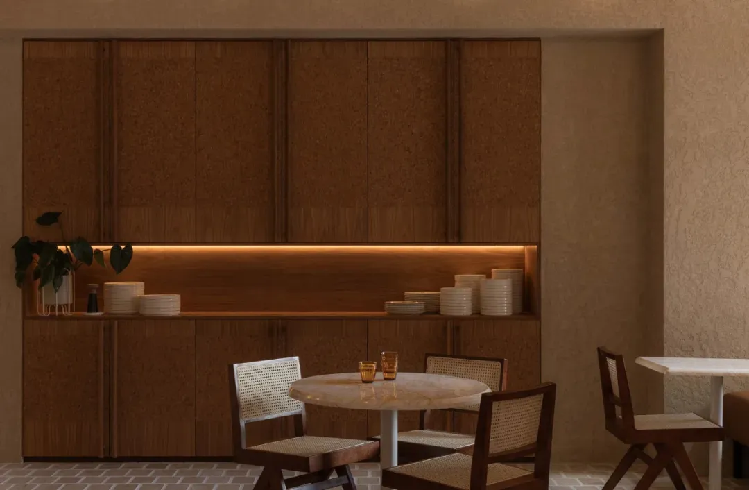 A cozy dining room with a wooden table and chairs, surrounded by cups and bowls, in a warm and intimate atmosphere