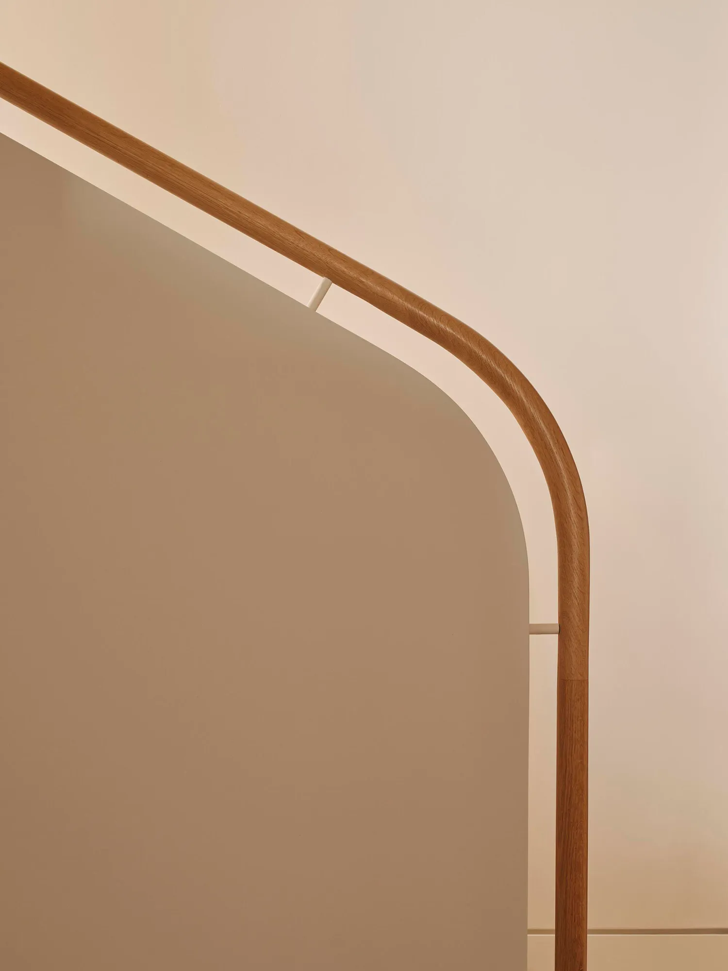 A staircase with a wooden handrail in a white room, creating a calm and serene atmosphere