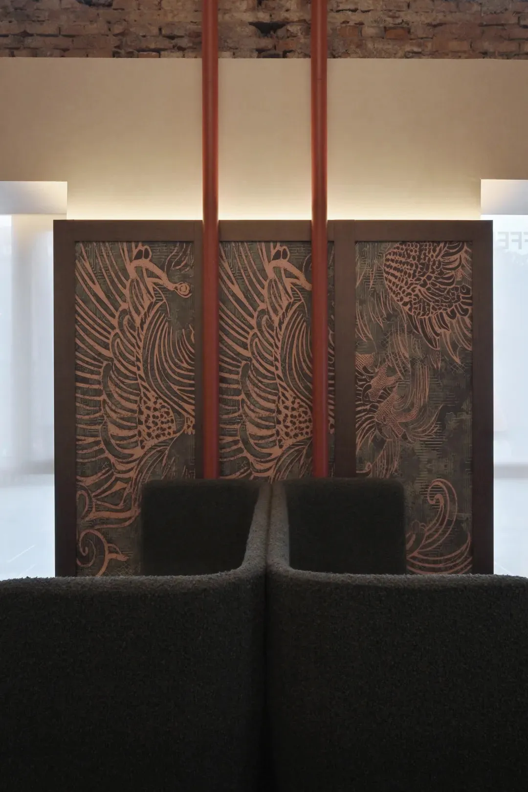 A waiting area with a wooden wall and a large bird painting, two chairs facing the painting, creating a warm and inviting space with a sense of elegance and sophistication