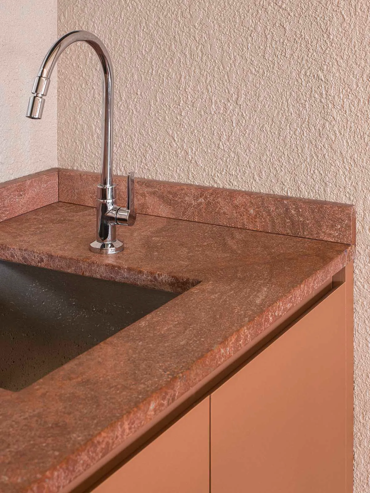 A bathroom with a marble sink and countertop, brown color scheme, and dim lighting