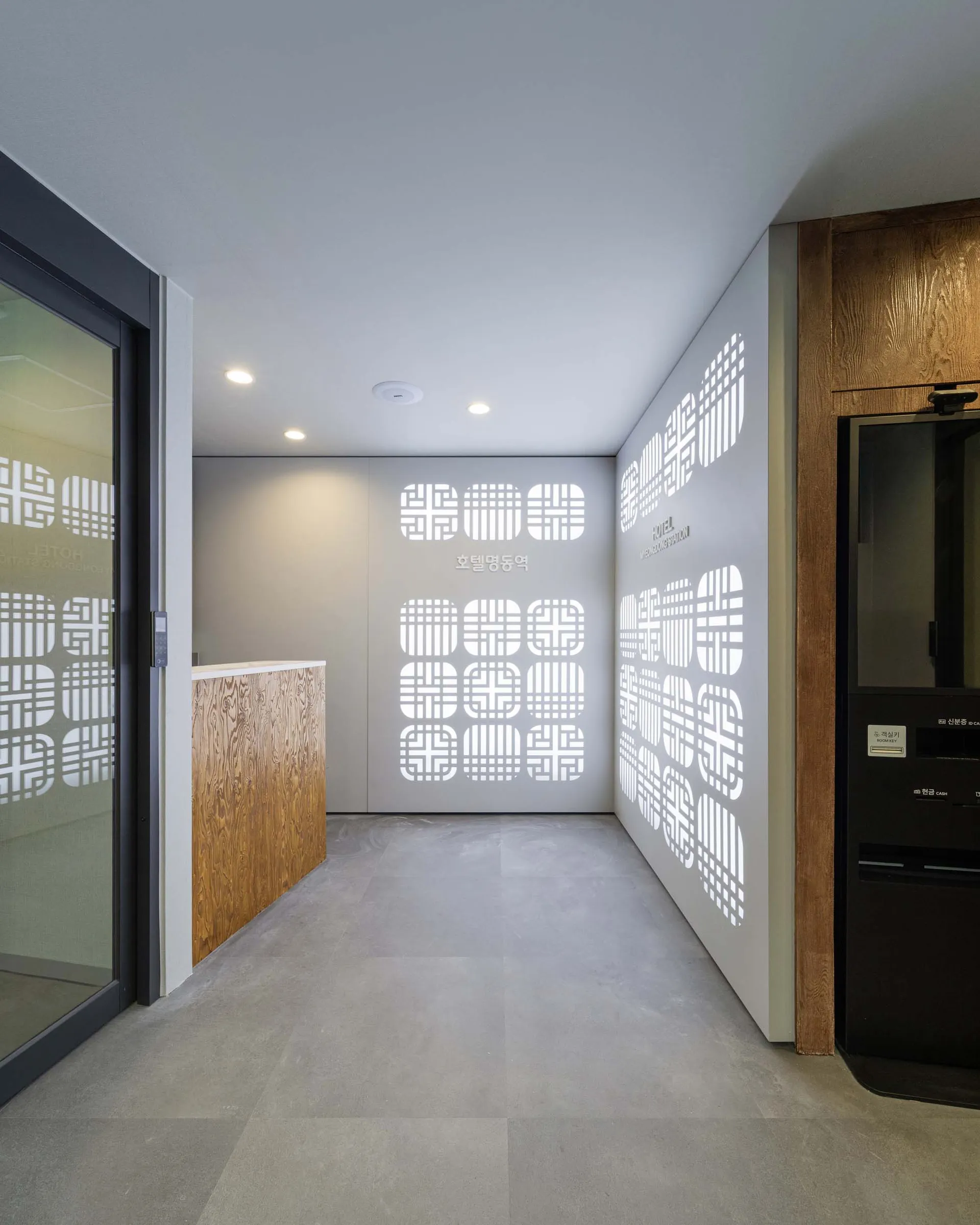 A dimly lit room with a gray floor, a white wall, and a wooden counter, creating a moody atmosphere