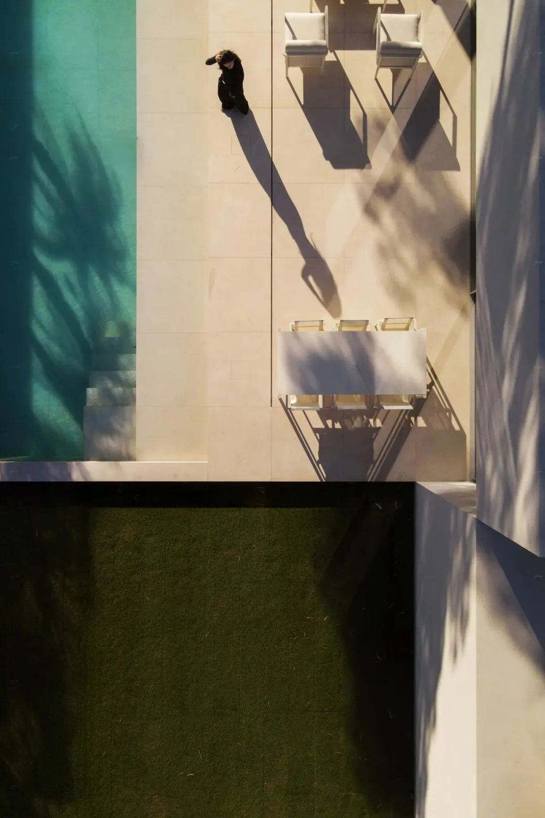 A serene outdoor space with a white table and chairs on a grassy area, surrounded by natural elements and illuminated by sunlight