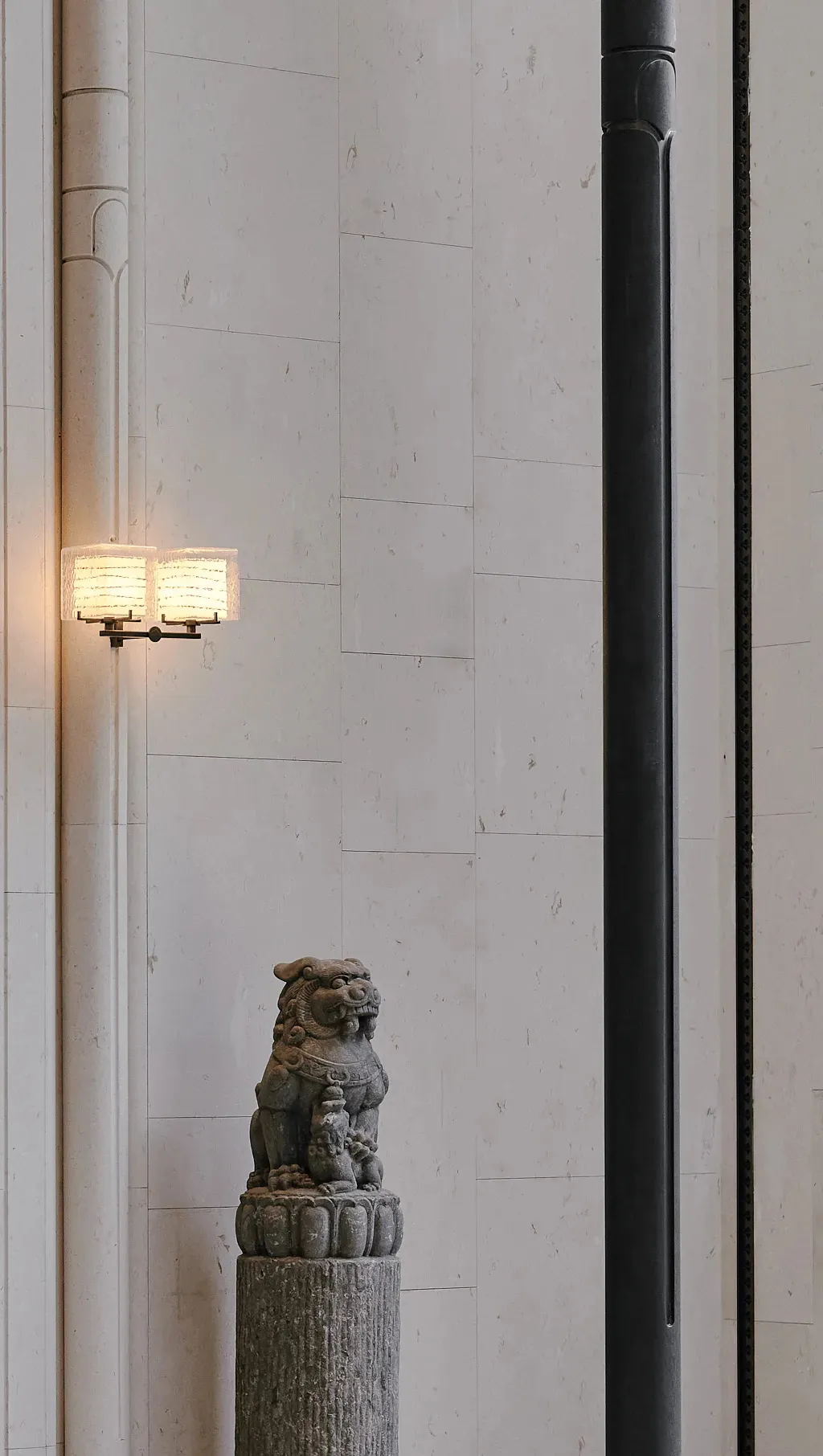 A dimly lit living space with a stone wall, stone floor, and a stone statue on a pedestal