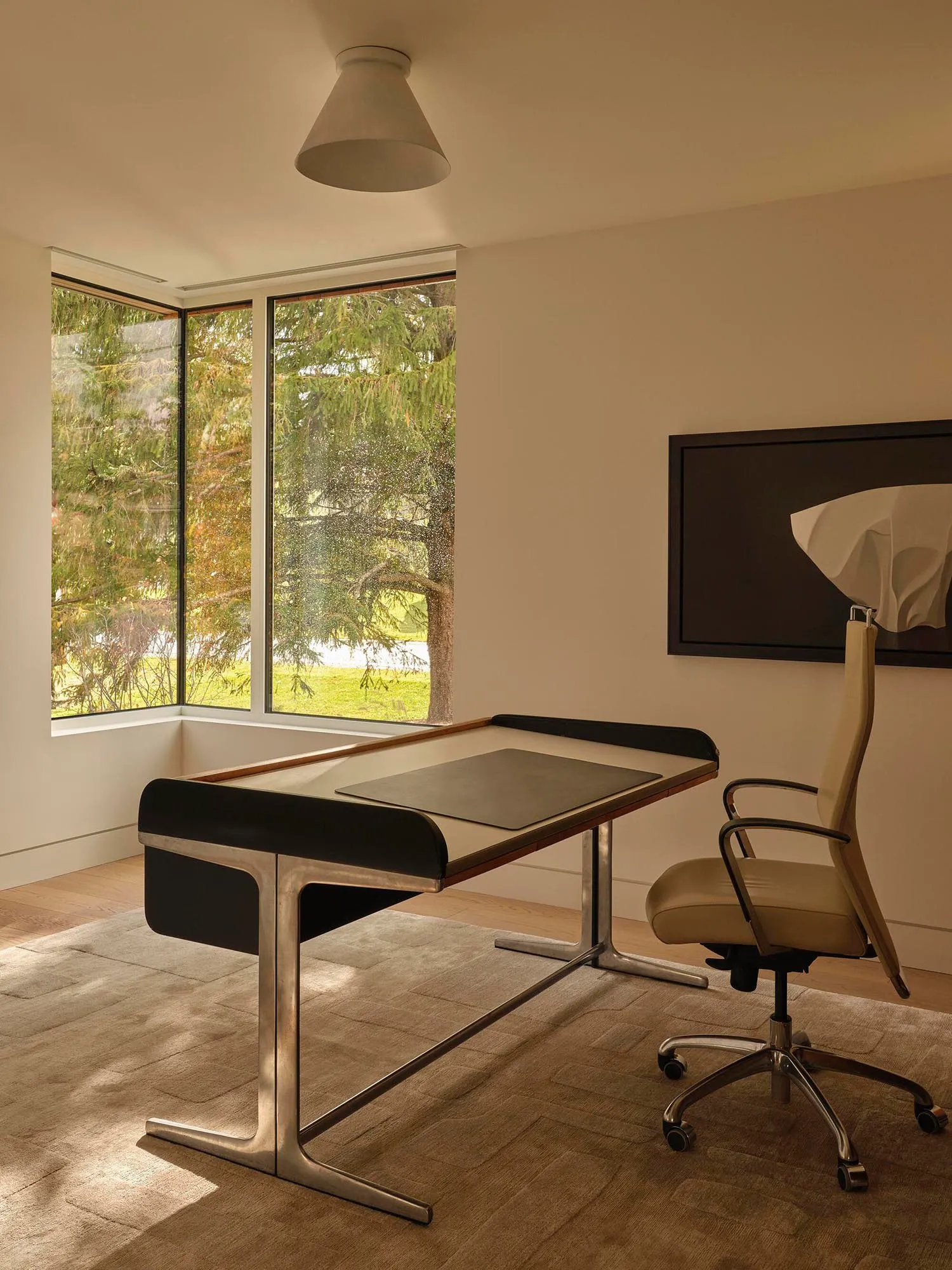A home office with a black desk and white chair, situated next to a window for natural light, in a clean and organized space