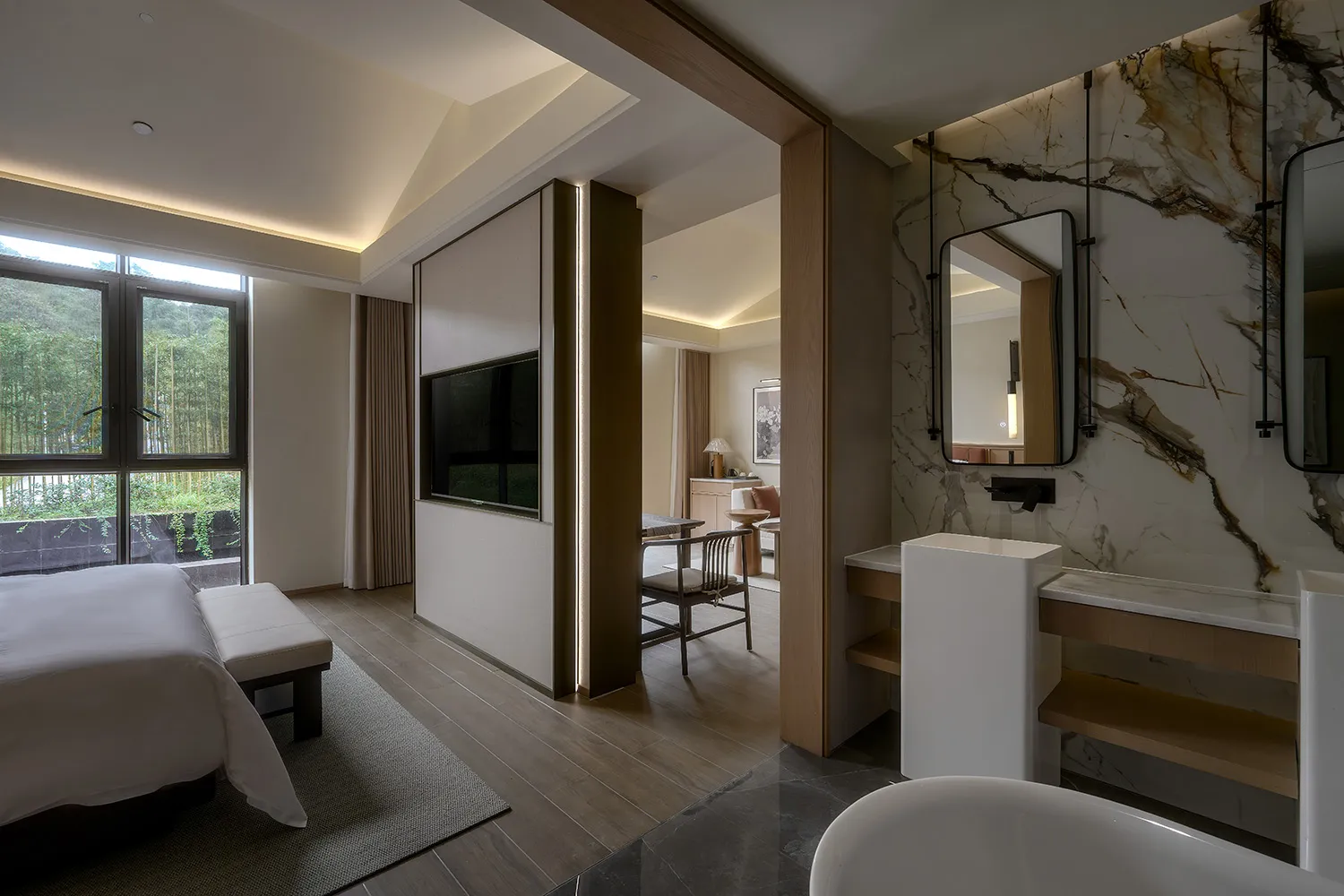 A modern hotel room with a bed, TV, chair, and desk, featuring wooden floors and a marble countertop, in a well-lit and inviting space