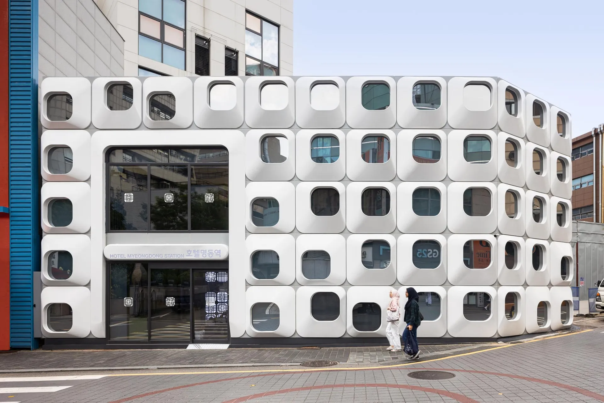 A modern building with a white facade and grid-like windows, set against a bright and sunny day