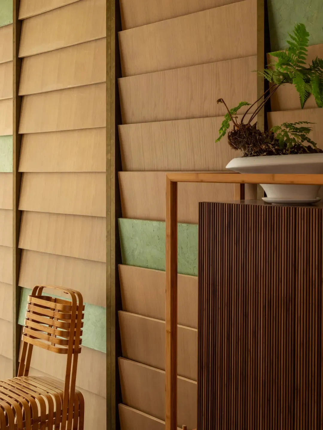 Warm and inviting living space with wooden walls, a wooden chair, and a potted plant on a shelf