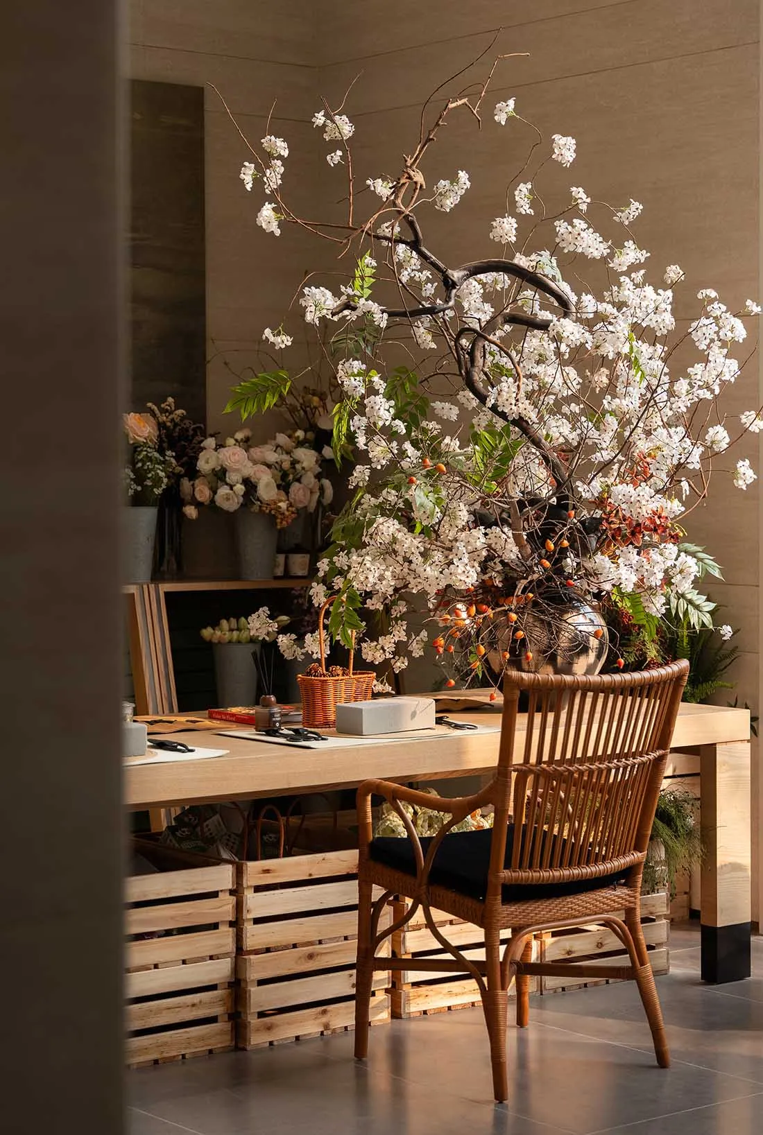 A wooden dining table surrounded by chairs and vases, set against a stone wall in a warm and inviting room