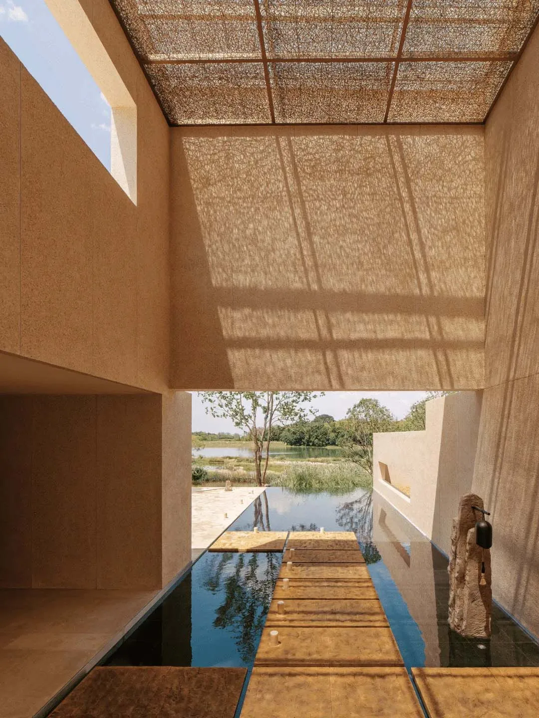 A modern building with a wooden deck and pool, surrounded by natural sunlight and a relaxing atmosphere