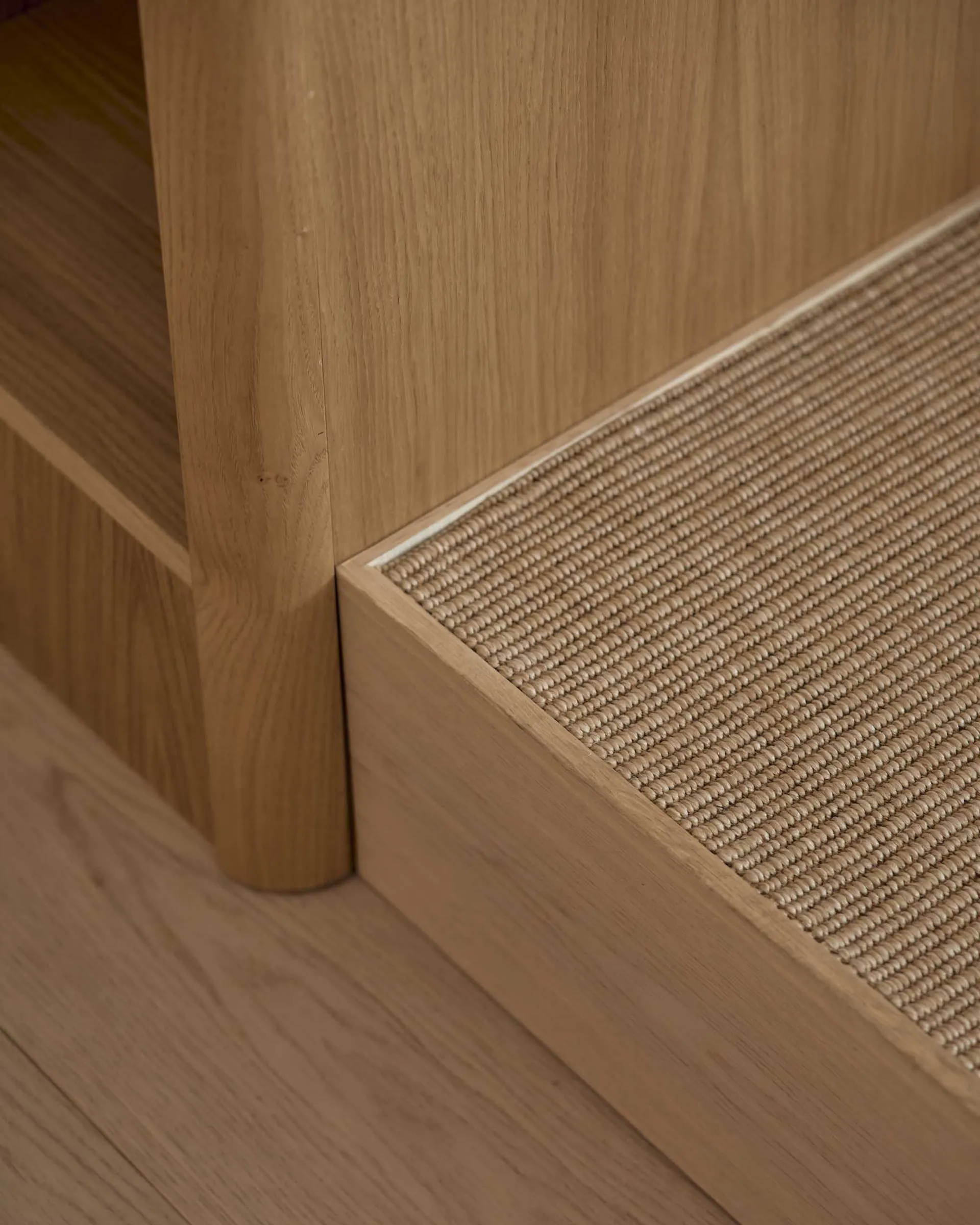 A residential space with a wooden floor and carpeted step, lit by natural sunlight from a window, creating a warm and cozy atmosphere