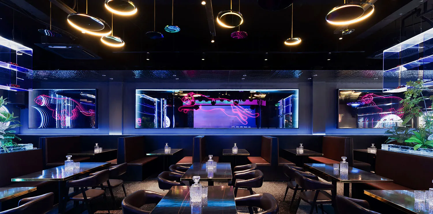 Elegant restaurant interior with black and purple decor, wine glasses, and dim lighting