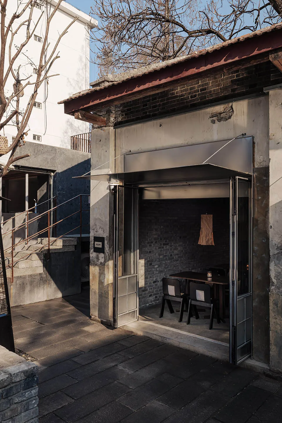 Dimly lit dining space with a wooden table and chairs, surrounded by a doorway and metal fixtures, in a warm and inviting atmosphere