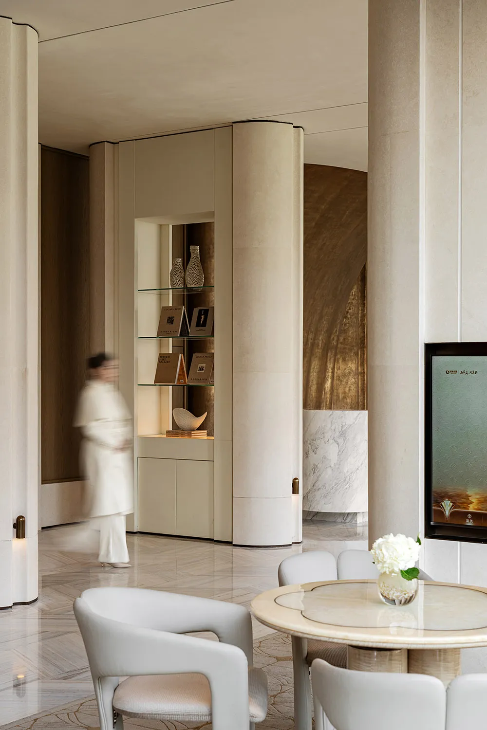 Elegant modern living space with a large TV, dining table, and chairs, decorated with vases and featuring a well-lit atmosphere