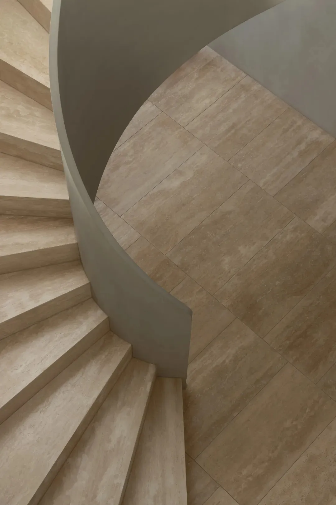 A curved stone staircase with visible steps, set in a building with natural light from above, creating a bright and inviting atmosphere