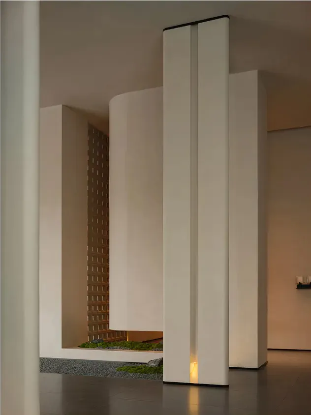 A large, open room with a white color scheme, white pillars, and a small garden area with a potted plant, creating a clean and minimalistic atmosphere