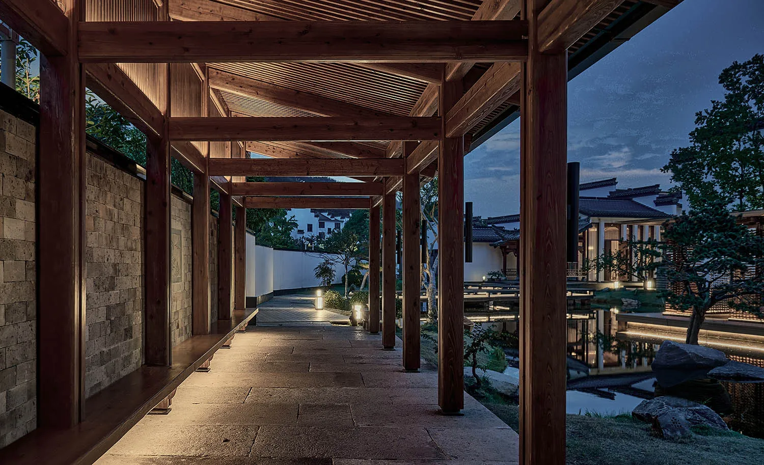 A warm and inviting hallway with wooden pillars, a wooden roof, and a bench near the entrance, illuminated by lights