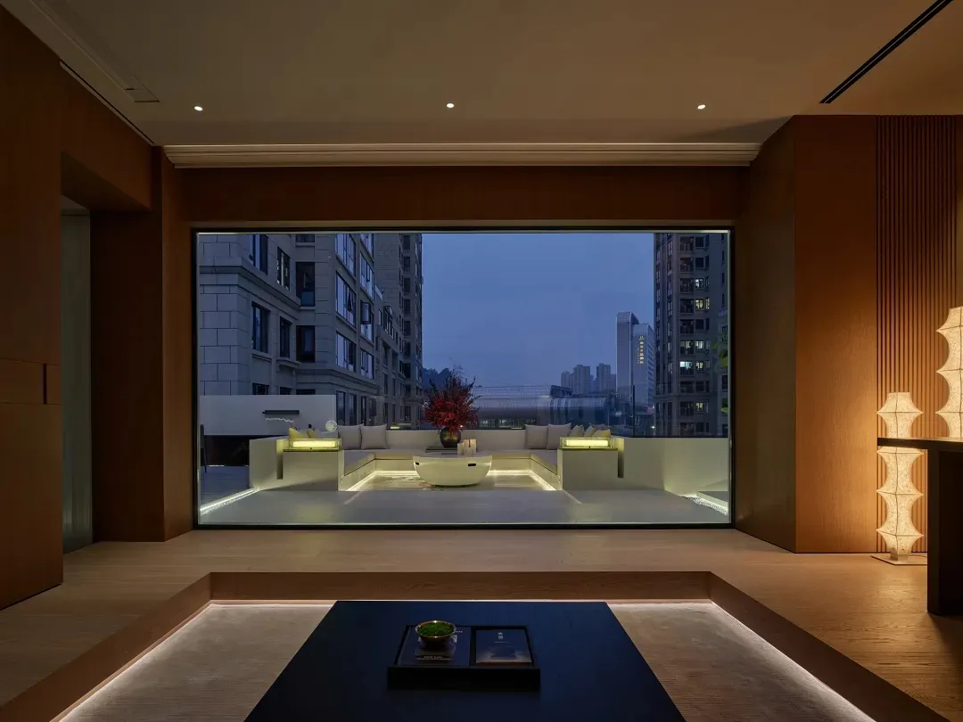 A well-lit living room with a couch, chair, and dining table, featuring wood and glass materials and a modern style