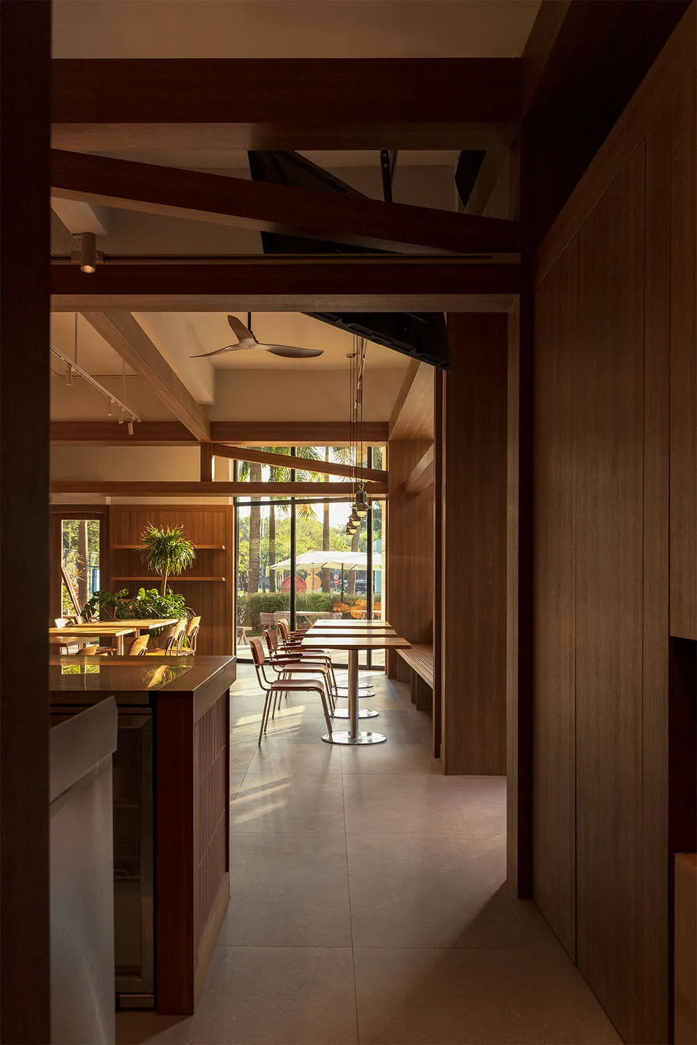 Cozy modern restaurant interior with a wooden dining table and chairs, dim lighting, and a visible kitchen counter in the background