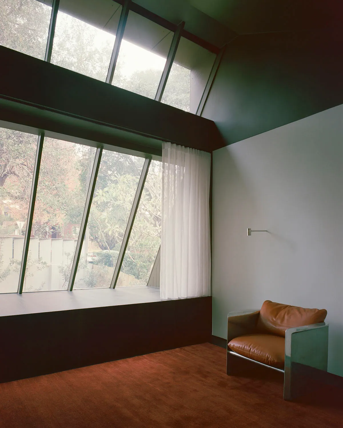 A black and white photograph of a room with a chair and a window, featuring a cozy atmosphere and natural light