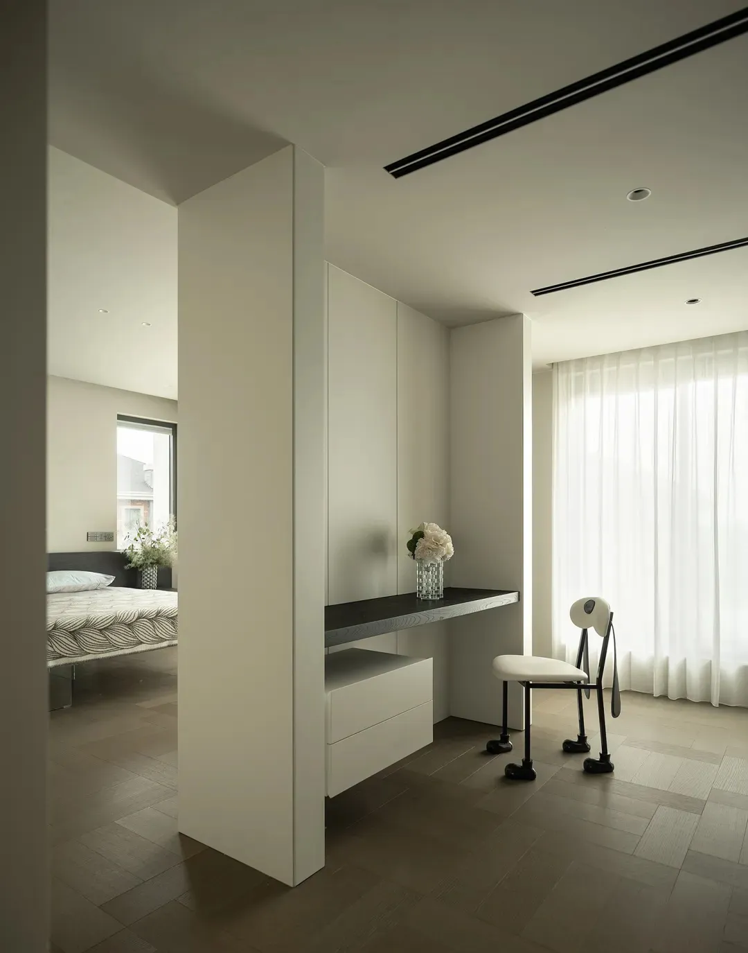 A modern bedroom with a white color scheme, featuring a bed, chair, desk, and mirror, with a focus on simplicity and clean lines, and soft diffused lighting