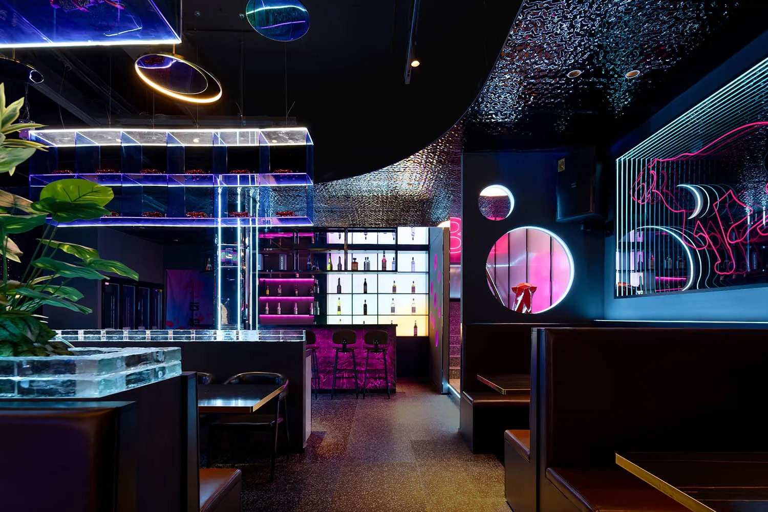 A modern restaurant with a bar area, black and purple colors, and dim lighting creating a sophisticated and inviting atmosphere