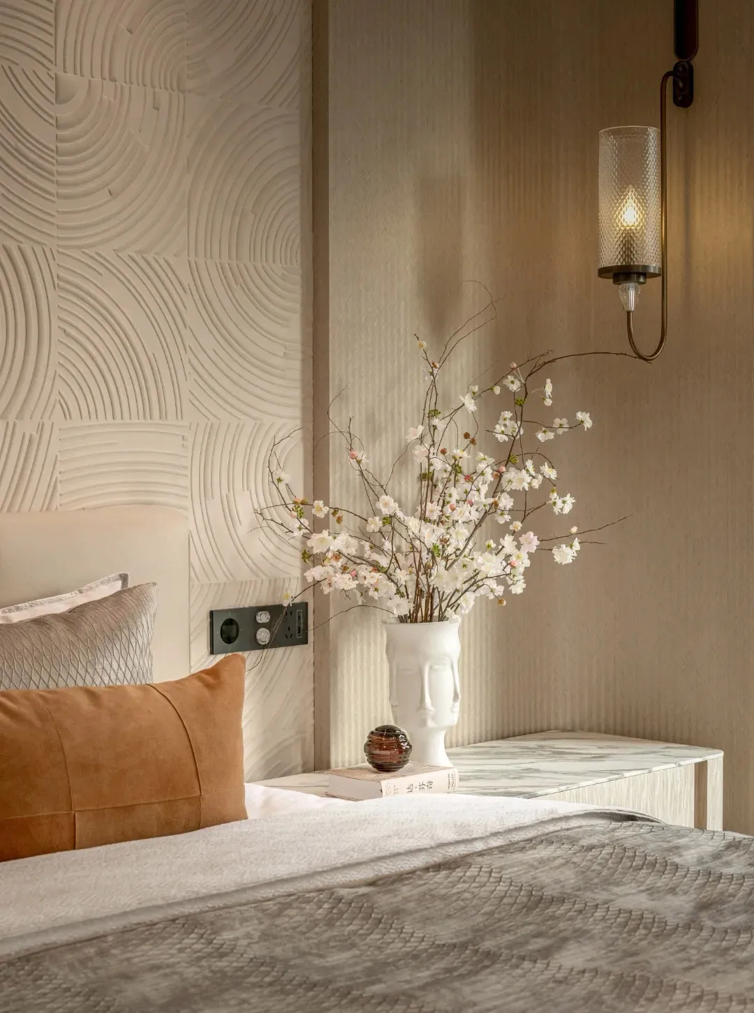 Cozy bedroom with a bed, nightstand, and vase with flowers on a patterned wallpaper background